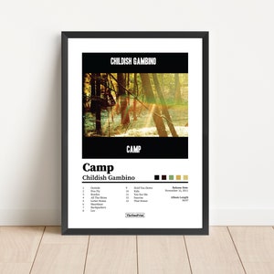 May include: A framed poster featuring the album art for Childish Gambino's "Camp." The poster has a black frame and a white background. The album art shows a forest scene with sunlight. The album title and artist name are displayed in bold text.