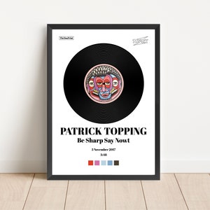 May include: A framed art print featuring a black vinyl record design with a colorful, stylized face in the center. The print includes the text "PATRICK TOPPING Be Sharp Say Nowt" and the date "3 November 2017".