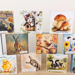 May include: A collection of eleven square wooden blocks featuring various colourful illustrations and text. Designs include a race car, a kitten, mushrooms, a chicken, a hare, a bird with coffee, flowers with bees, a blue tit, a chick, a donkey, a cow, and an otter.