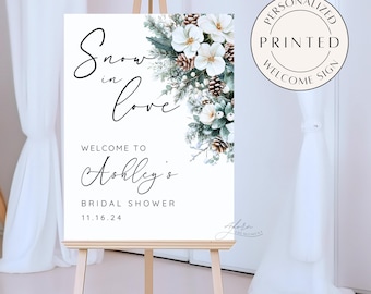 Puede incluir: Un cartel de bienvenida blanco para una despedida de soltera con un diseño floral invernal y el texto "Snow in love" y "Bienvenido a Ashley's Bridal Shower 11.16.24".