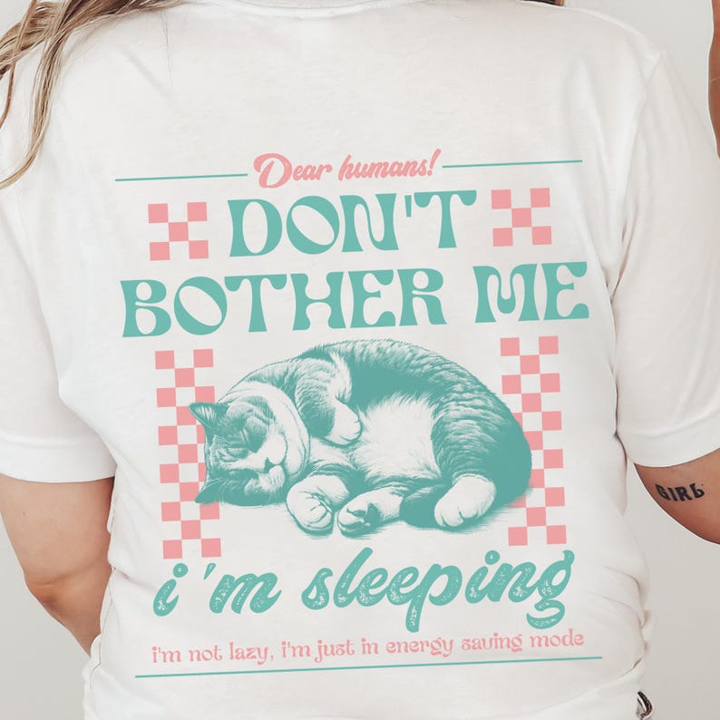 May include: White t-shirt with a pink and blue graphic of a cat sleeping with the text "Dear humans! Don't bother me I'm sleeping I'm not lazy, I'm just in energy saving mode."