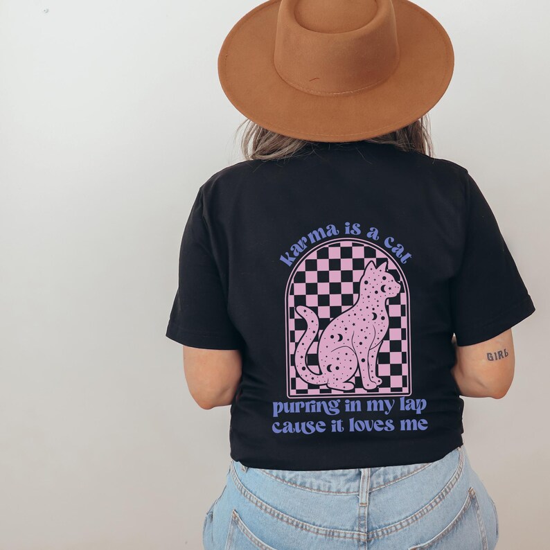 May include: Black t-shirt with a pink cat graphic and the text "karma is a cat purring in my lap cause it loves me".