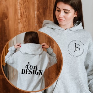 Może przedstawiać: Szara bluza z kapturem z czarnym logo w kształcie koła z przodu, na kt&oacute;rym widnieje napis "Dein Design" oraz litery "J" i "S" wewnątrz koła. Na plecach bluzy znajduje się napis "Dein Design" w kolorze czarnym.