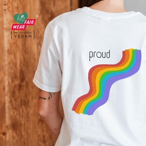 May include: White t-shirt with a rainbow design and the word "proud" printed on the back.