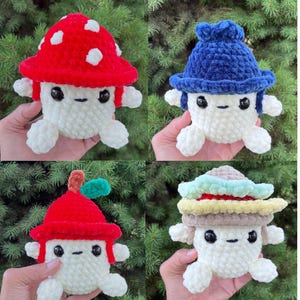 May include: Four small, round, crocheted plush toys with white bodies, black bead eyes, and simple stitched mouths. Each toy wears a different textured hat: a red mushroom cap with white spots, a blue hat, a red fruit-like cap, and a layered hat.