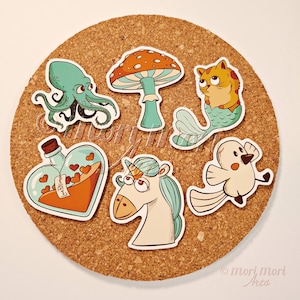 Könnte beinhalten: Eine Sammlung skurriler Aufkleber mit einem Oktopus, einem Pilz, einer Katzenmeerjungfrau, einer Liebestrankflasche, einem Einhorn und einem Vogel. Die bunten Aufkleber im Cartoon-Stil eignen sich perfekt zum Dekorieren von Notizbüchern oder persönlichen Gegenständen.