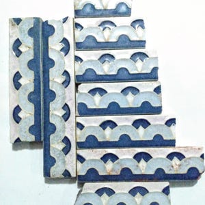 May include: A set of blue and white ceramic tiles with a scalloped design. The tiles are arranged in a staggered pattern, creating a wave-like effect.