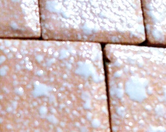 May include: Close-up of a pink and white tiled surface. The tiles have a speckled pattern with white flecks on a pink background.
