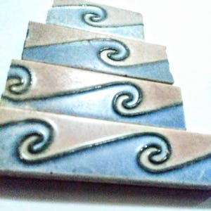 May include: Stack of five ceramic tiles with a wave pattern and a swirl design in shades of blue, brown, and white.