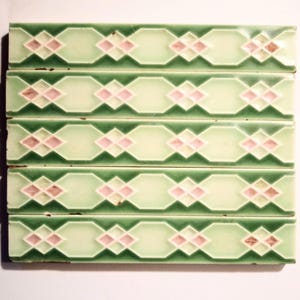 May include: Five green and white ceramic tiles with a pink diamond pattern. The tiles are arranged in a row, with the top tile being the oldest and the bottom tile being the newest.