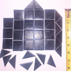 May include: A set of black and gray ceramic tiles in a geometric pattern. The tiles are arranged in a house shape with a measuring tape next to it. The tiles are about 1 inch square.
