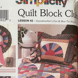 Pode incluir: Pacote de padrões Simplicity Quilt Block Club, lição #2, com os blocos Grandmother's Fan & Bow Tie. O pacote mostra uma colcha, uma coroa e um travesseiro com um design de patchwork colorido.