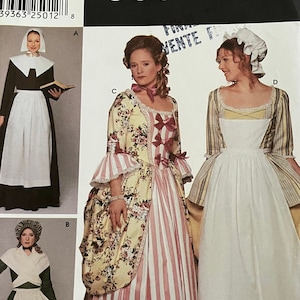 Peut inclure: Un patron de couture Simplicity Costumes présentant quatre modèles de costumes historiques différents. Le patron comprend une robe d'époque coloniale avec une jupe à rayures et un corsage fleuri, une robe d'époque coloniale avec un tablier blanc, une robe d'époque coloniale avec un tablier blanc et un corsage vert, et une robe d'époque coloniale avec un tablier blanc et un corsage noir.
