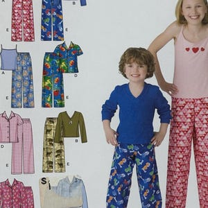 Peut inclure: Patron de couture Simplicity pour pyjamas enfants. Le patron propose différents styles de pyjamas, avec des options pour hauts et bas. L'image montre des exemples de pyjamas finis, dont un débardeur rose avec des cœurs et un pantalon à motifs.
