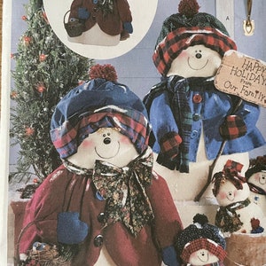 Puede incluir: Un patrón de costura Butterick con diseños de muñecos de nieve. El patrón incluye instrucciones para crear muñecos de nieve con varios atuendos, sombreros y accesorios. La imagen muestra varios muñecos de nieve terminados, algunos sosteniendo cestas y letreros. El texto "Happy Holidays From Our Family!" es visible.