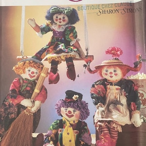 May include: Simplicity Crafts sewing pattern featuring clown dolls. The pattern includes instructions for creating several colorful clown dolls with various accessories. The image shows the finished dolls, including one on a swing and another holding a broom.