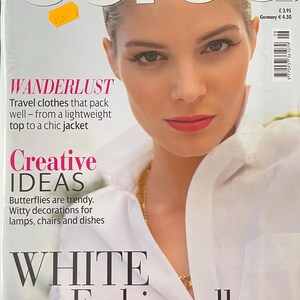 Op de afbeelding: Een tijdschriftomslag met het woord "Burda" in grote letters. De cover toont een vrouw met een lichte huid en rode lippenstift. Tekst bevat "WANDERLUST", "Creative IDEAS" en "WHITE Fashion album".