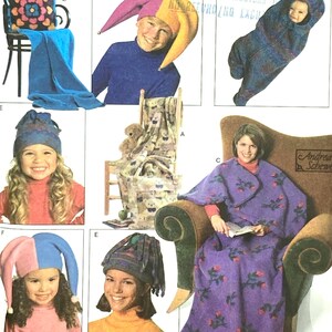Puede incluir: Patrón de Simplicity Crafts con varios proyectos de costura. Incluye un gorro de bufón, un saco para bebé, una manta, una almohada y otros artículos. El patrón está etiquetado como "7406" y "Talla única."