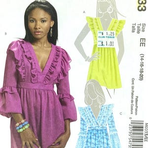 Peut inclure: Une enveloppe de patron de couture McCall's avec une tunique magenta à manches à volants et col en V. L'enveloppe comprend des illustrations de modèles de robes similaires en jaune et bleu, avec le numéro de patron M6033.