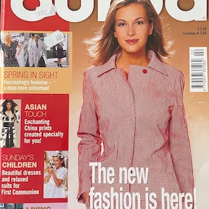 Op de afbeelding: Een tijdschriftomslag van "Burda World of Fashion" met een vrouw in een rood-wit geruite jas. De tekst op de omslag luidt: "The new fashion is here!" en "Feminine styles whet your sewing appetite!" met de datum 2/2002.