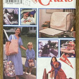 May include: Simplicity Crafts sewing pattern packet. The packet features a variety of craft projects, including a chair cover, bags, and children's accessories. The main text on the packet reads "Crafts" in red. The packet is white with several images.