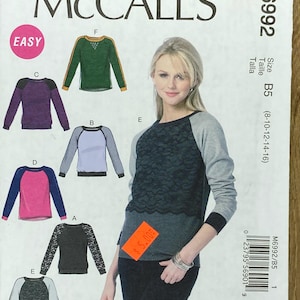 May include: A McCall's sewing pattern, M6992, for a top, showcasing several design variations. The pattern includes images of tops with long sleeves and colour-blocked designs. The word "EASY" is printed on the pattern.
