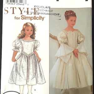 May include: Simplicity sewing pattern for girls' dresses. The pattern features two dress designs, both with long skirts and detailed bodices. The cover includes the text "Simplicity" and "Style for Simplicity" with the designer's name, Barbara Canfer.