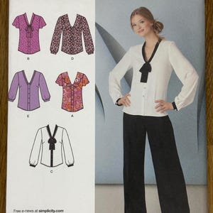 Pode incluir: Padrão de costura Simplicity 1779 U5, apresentando uma mulher em uma blusa branca com acabamento preto e calças pretas. O padrão inclui vários designs de blusas: um top rosa com bolinhas, um top com estampa floral, uma camisa roxa com botões e um top com estampa floral.