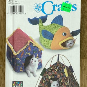 Könnte beinhalten: Simplicity Crafts Schnittmuster 9004 mit Designs für Katzenbetten. Das Muster enthält ein fischförmiges Bett, ein hausförmiges Bett und ein zeltförmiges Bett. Das Muster ist mit "ONE SIZE" gekennzeichnet und enthält ein Preisschild.