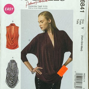 Peut inclure: Patron de couture McCall's M6841 avec une femme portant un haut bordeaux à encolure drapée. Le patron comprend des illustrations de différents styles de hauts et le mot "EASY" dans un cercle rose.