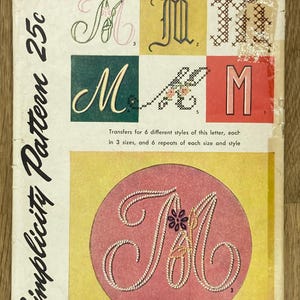 Può includere: Modello di trasferimento per ricamo Simplicity vintage con la lettera "M" in vari stili. La copertina mostra la lettera in diversi caratteri e motivi di cucitura, con il testo "Embroidery Transfer" e "Simplicity Pattern 25c".