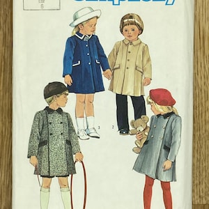 Può includere: Busta del modello di cucito Simplicity con illustrazioni di cappotti per bambini. La busta ha il numero 6661 e la parola "Simplicity" in blu. I bambini indossano cappotti blu, beige, grigi e verdi fantasia.