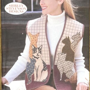 May include: A Butterick sewing pattern for a vest with cat appliqués. The vest has a quilted design with a grid pattern and is trimmed with a dark brown border. The pattern includes the text "5289" and "Shirley Stevenson Designs".