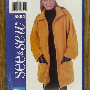 May include: A yellow fleece jacket with a zipper closure and two pockets. The jacket has a drawstring at the bottom and a high collar. The pattern number is 5804 and the size is A/6-8-10. The text "see & sew" is printed on the left side of the package in a blue and white font. The text "YES! It's easy" is printed in a blue and white font on the bottom left corner of the package.