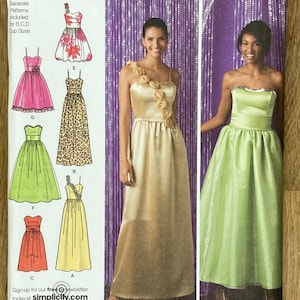 Peut inclure: Patron de couture Simplicity 2440 pour robes en tailles D5 4, 6, 8, 10, 12. L'enveloppe présente des illustrations de six modèles de robes et des photos de deux robes finies, une dorée avec des fleurs sur l'épaule et une vert clair.