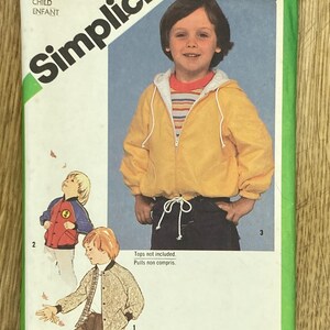 May include: A vintage Simplicity sewing pattern envelope for a child's jacket. The cover shows a young boy wearing a yellow hooded jacket. The text "Simplicity" is prominently displayed, along with the pattern number 9819.