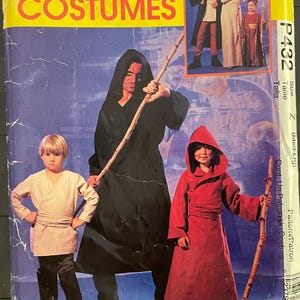 May include: A sewing pattern for costumes, featuring a black hooded robe, a red hooded robe, and a white tunic. The pattern is for sizes medium to large and is labelled "McCall's Costumes P432".
