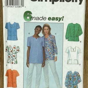 May include: A Simplicity sewing pattern packet showing different scrub top designs in blue, green, orange, and patterned fabrics. The packet includes the text "Simplicity" and "6 made easy!" with size information.