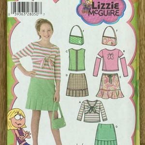 Puede incluir: Patrón de costura Simplicity con diseños de Lizzie McGuire. El patrón incluye opciones para una blusa a rayas, una falda plisada verde y un bolso. El patrón es para tallas 8-16 y también para tallas grandes de niñas 8 1/2 - 16 1/2.