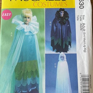 Puede incluir: Patrón de disfraces McCall's M6630. El paquete presenta tres diseños de disfraces: un vestido azul y verde con un gran cuello con volantes, una capa oscura con detalles verdes y una capa blanca con capucha. La palabra "EASY" está en un círculo rosa.