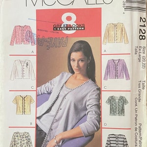 May include: A sewing pattern for a cardigan, featuring a model wearing a gray cardigan with a beaded trim. The pattern includes five different styles of cardigans, including a floral print, a striped cardigan, and a solid color cardigan. The pattern is for sizes 20 and 22, and is labeled as "Great Looks" and "1 Easy Pattern".