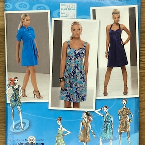 May include: A sewing pattern for a dress with a variety of styles. The pattern is inspired by Project Runway and includes instructions for making a blue dress with a button-up front, a blue and white floral dress with a sweetheart neckline, and a navy blue halter dress. The pattern is for sizes 12-20.