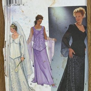 Puede incluir: Patrón de costura Simplicity 8923 con ilustraciones de tres vestidos formales. La portada muestra un vestido de novia blanco con velo, un vestido morado con mangas fluidas y un vestido de noche negro con falda de encaje.
