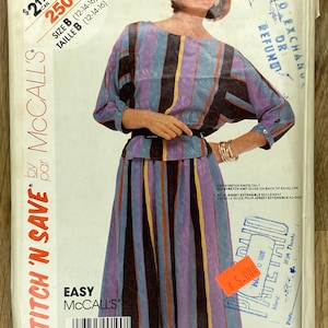 May include: Vintage McCall's sewing pattern featuring a woman wearing a striped dress. The pattern envelope displays the text "STITCH 'N SAVE" and "EASY McCall's". The dress has vertical stripes in shades of purple, blue, and brown.