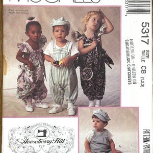 Puede incluir: Sobre de patrón de costura McCall's con diseños de ropa infantil. La portada muestra a tres niños con diferentes conjuntos, incluyendo monos y un mono floral. El patrón es de Gooseberry Hill.