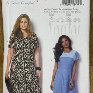 Puede incluir: Un patrón de costura Butterick, B6033, con dos diseños de vestidos. Uno tiene un estampado de cebra en blanco y negro, y el otro es un vestido azul liso con un canesú azul más claro. El patrón incluye tallas para mujer.