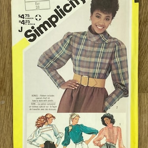 May include: Simplicity pattern envelope showing a woman in a plaid blouse and skirt. The envelope includes illustrations of other blouse designs. The text on the envelope reads "6034" and "Pattern/Patron".