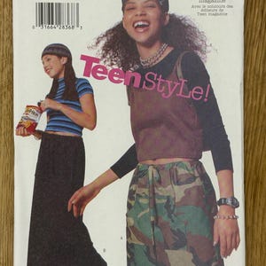 Può includere: Una busta di cartamodello Butterick con due modelle che indossano abiti. Il modello include una gonna mimetica, un top marrone e una camicia a righe. Il testo "Teen StyLe!" è visibile.