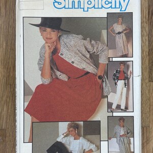 Peut inclure: Un patron de couture Simplicity vintage avec une femme en robe rouge, veste grise et chapeau noir. Le patron propose plusieurs options de tenues, avec le logo Simplicity en bleu. Le numéro du patron est 6744.