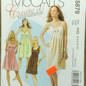 May include: McCall's sewing pattern M5879 featuring illustrations of various dresses. The pattern includes sizes AX5 (4-6-8-10-12). The cover displays a woman in a cream-colored dress with a floral detail.